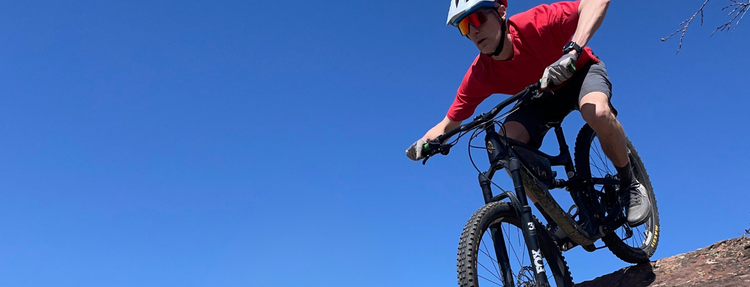 Person riding a mountain bike against a clear blue sky